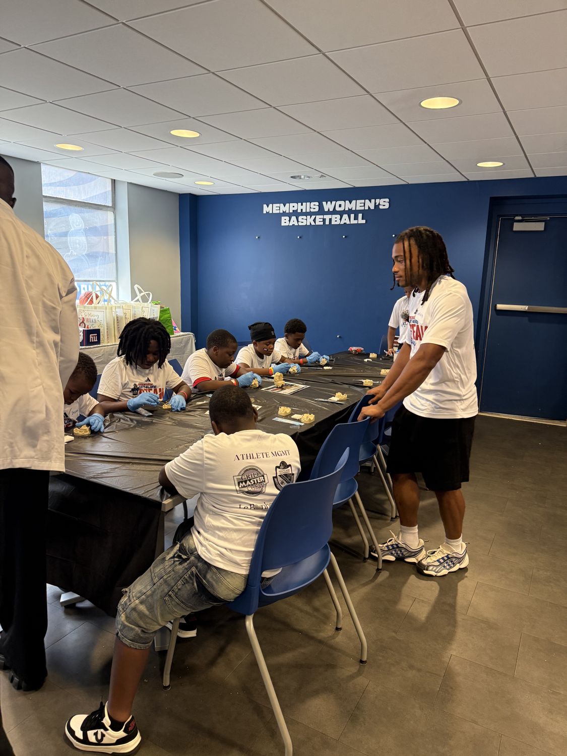 Kids at a hands-on learning station with an athlete